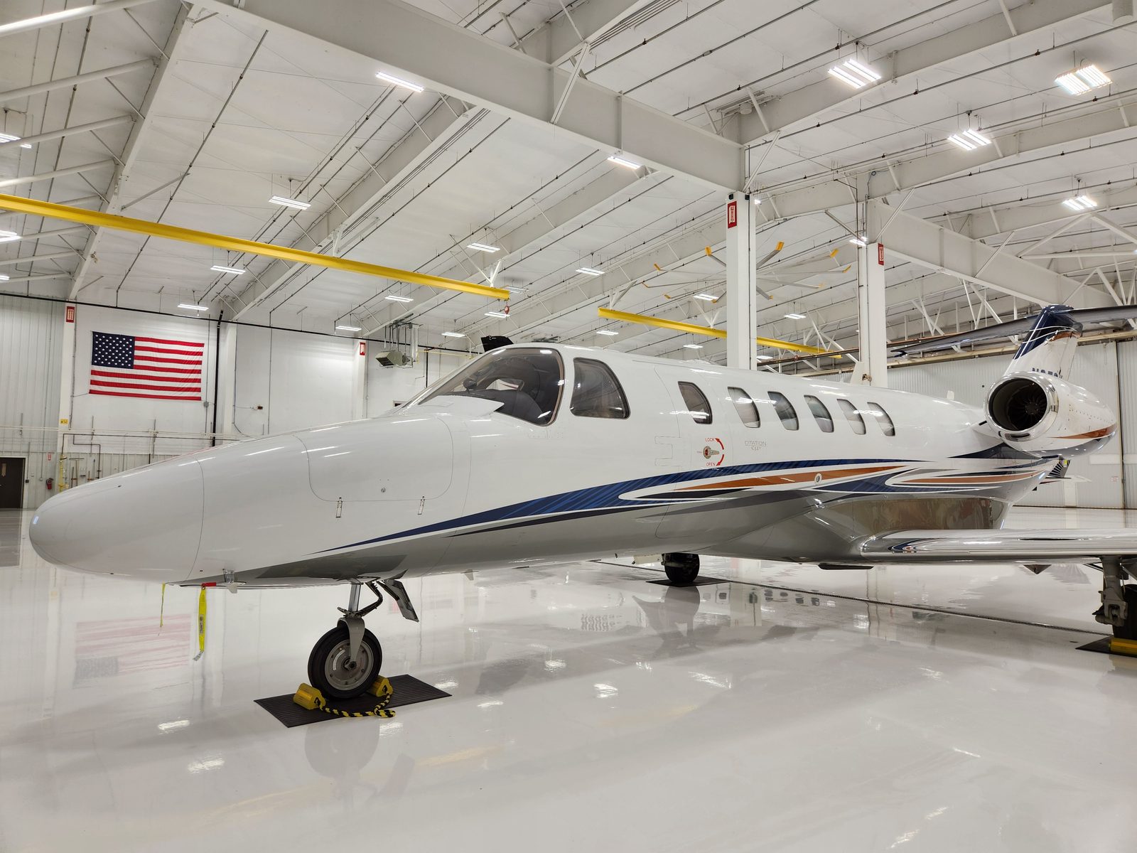 A Citation CJ2 in a bright, spotless hangar with an American flag on the far wall