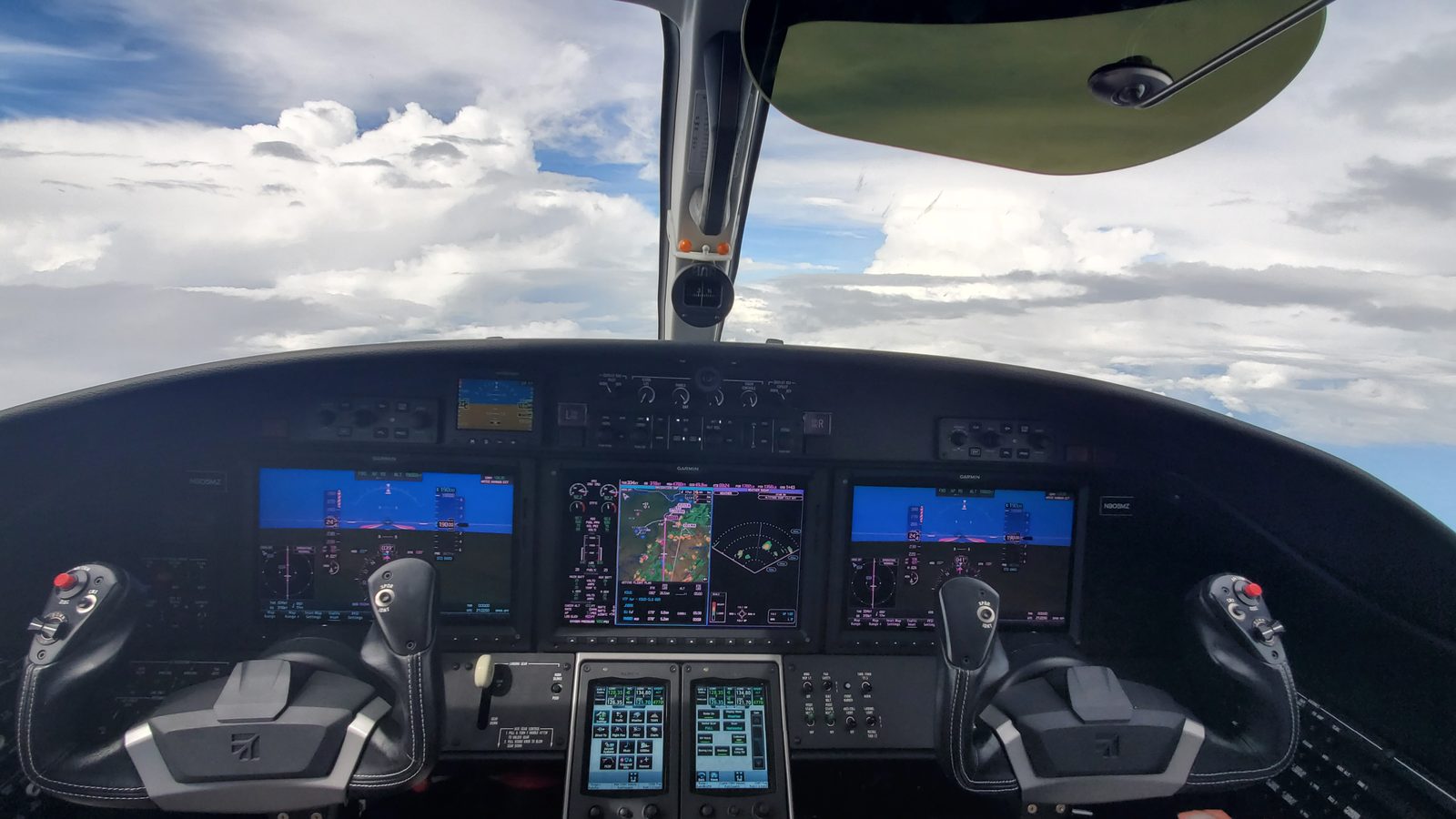 A Garmin-equipped Citation flight deck in cruise between towering cloud layers