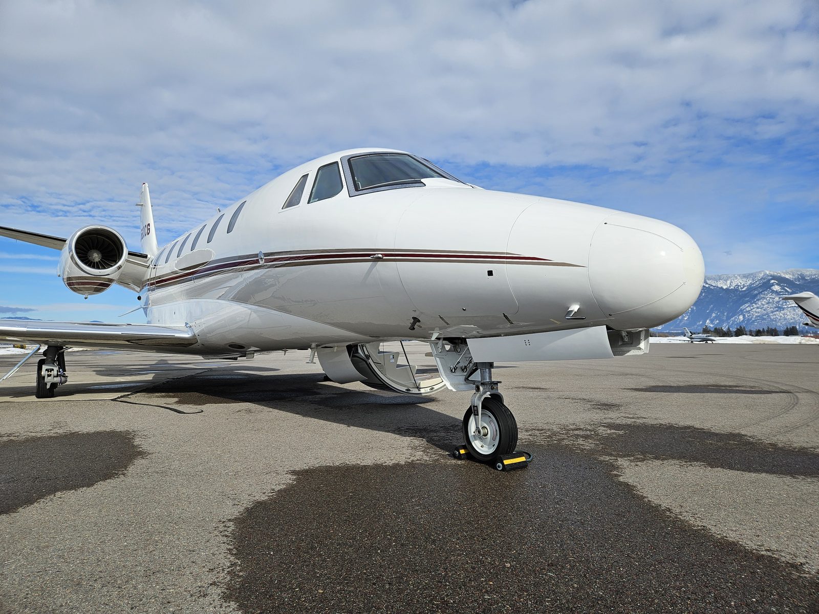 Citation Excel parked on a ramp with snow-covered mountains behind