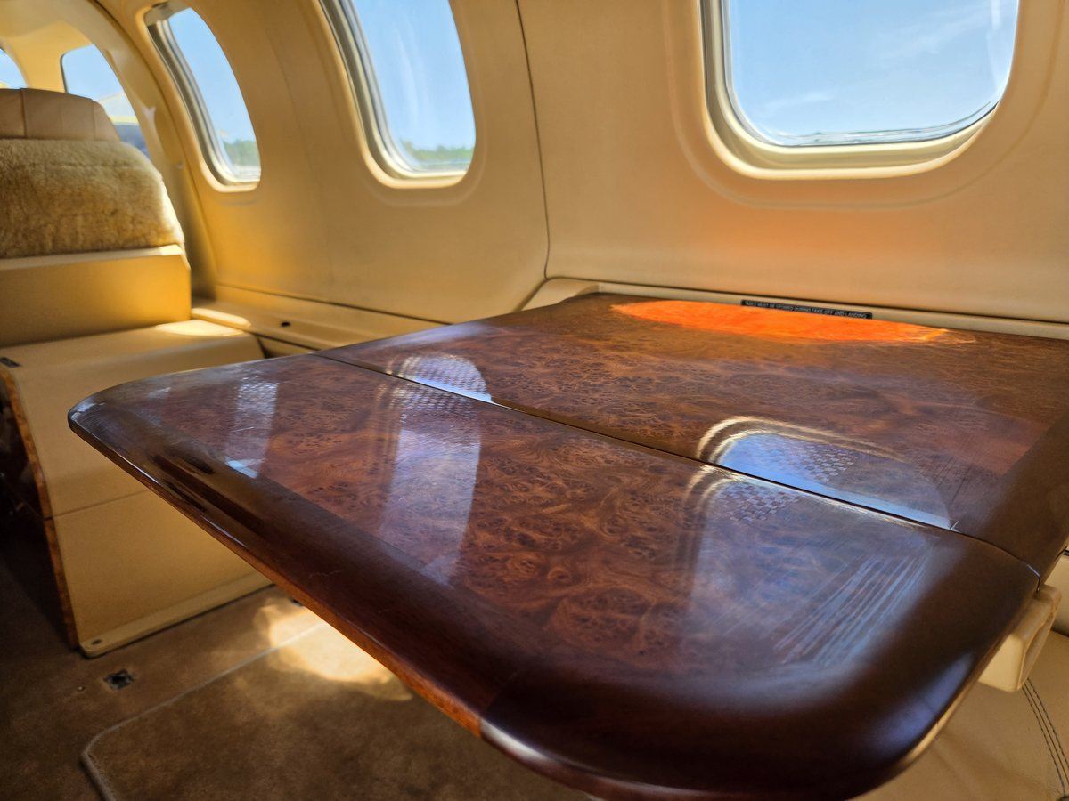 Polished burl wood executive table deployed in the cabin of TBM 700C2 N6272B in warm afternoon light